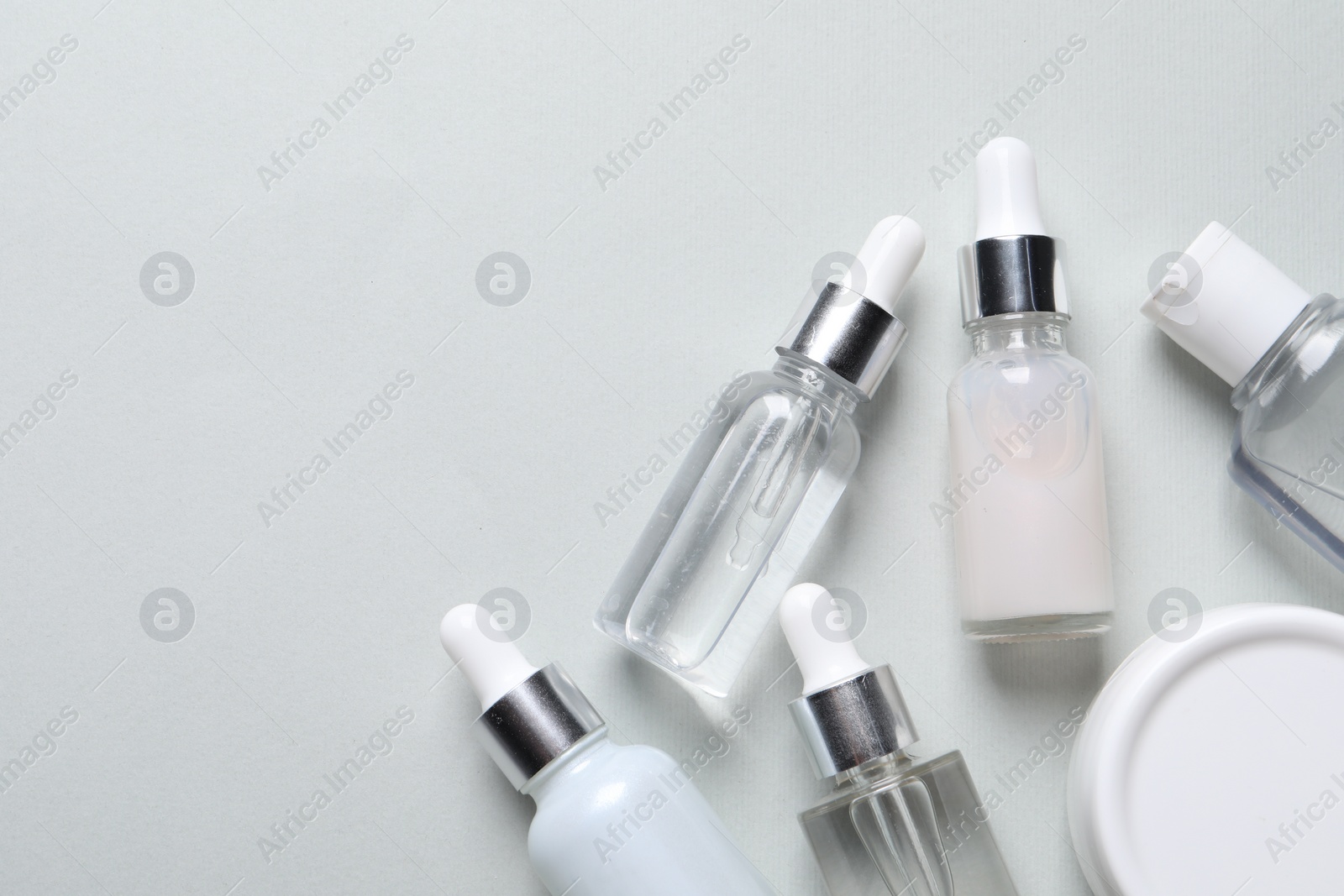 Photo of Many bottles of cosmetic serum on light grey background, flat lay. Space for text