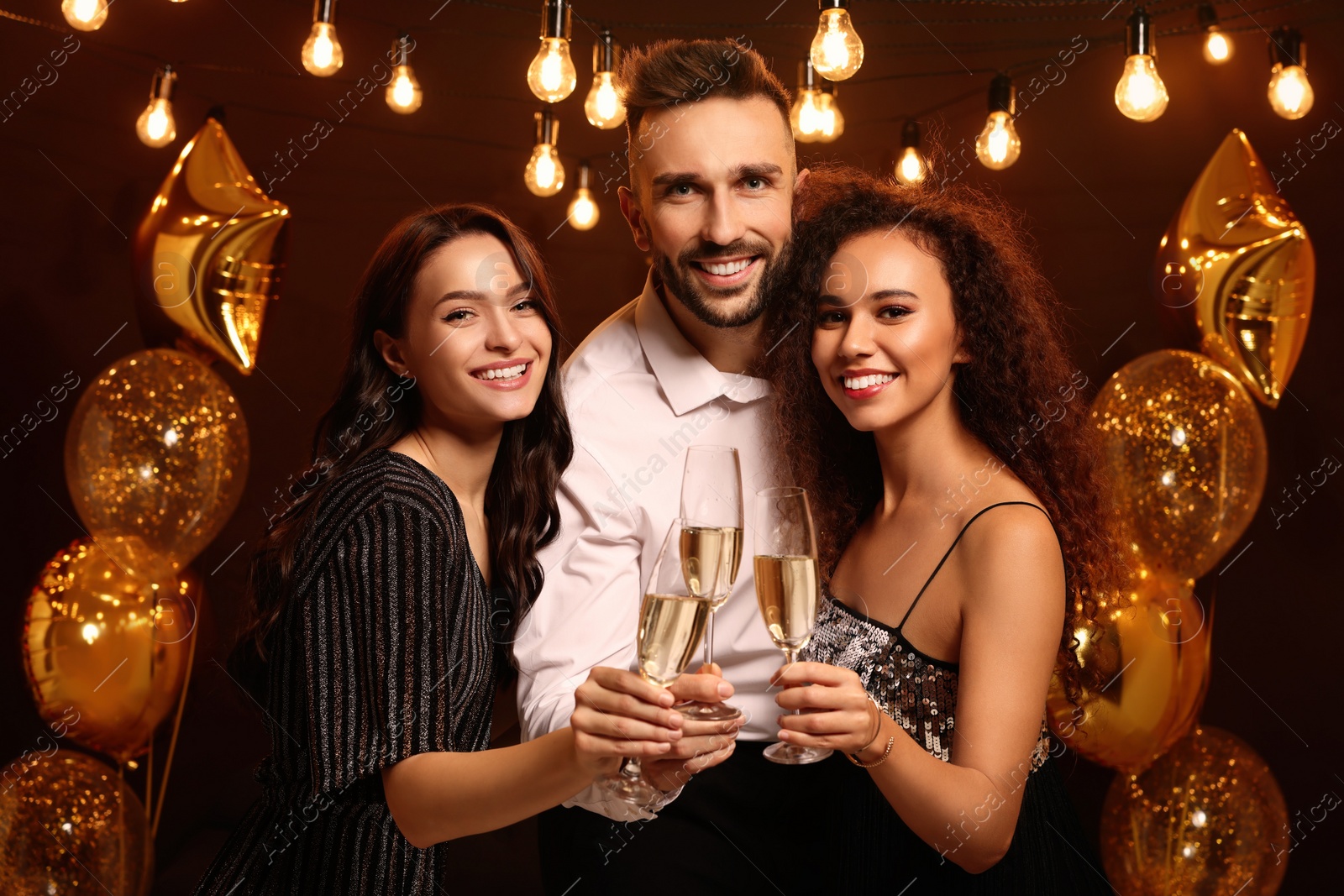 Photo of Happy friends with glasses of sparkling wine celebrating New Year indoors