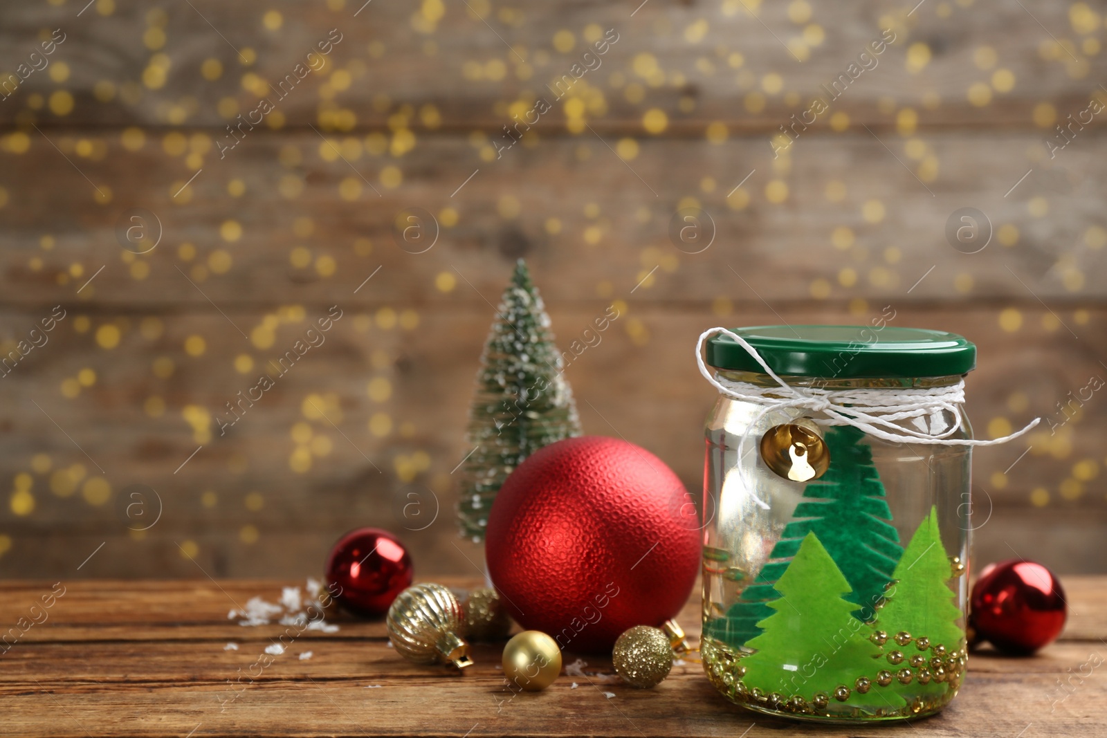 Photo of Handmade snow globe and Christmas decorations on wooden table, space for text