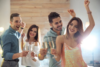 Photo of Friends clinking glasses with champagne at party indoors