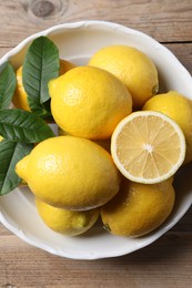 Fresh lemons and green leaves on wooden table, top view