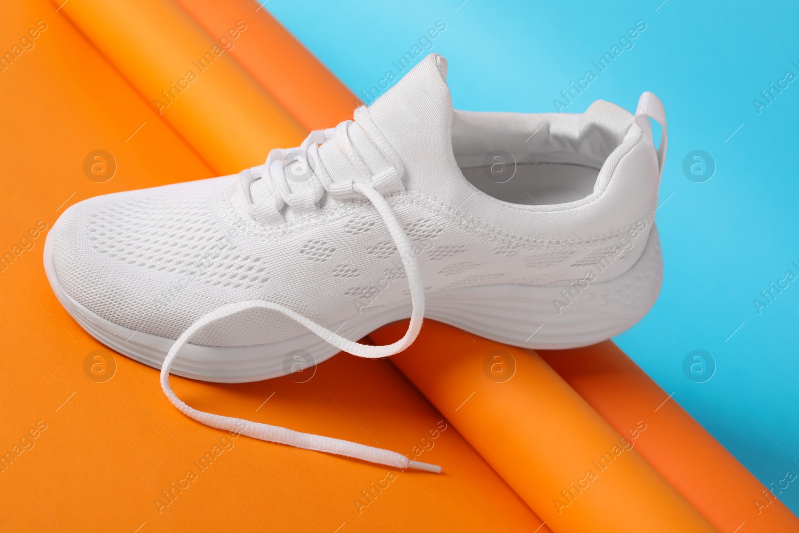 Photo of Stylish sportive shoe with white lace on color background