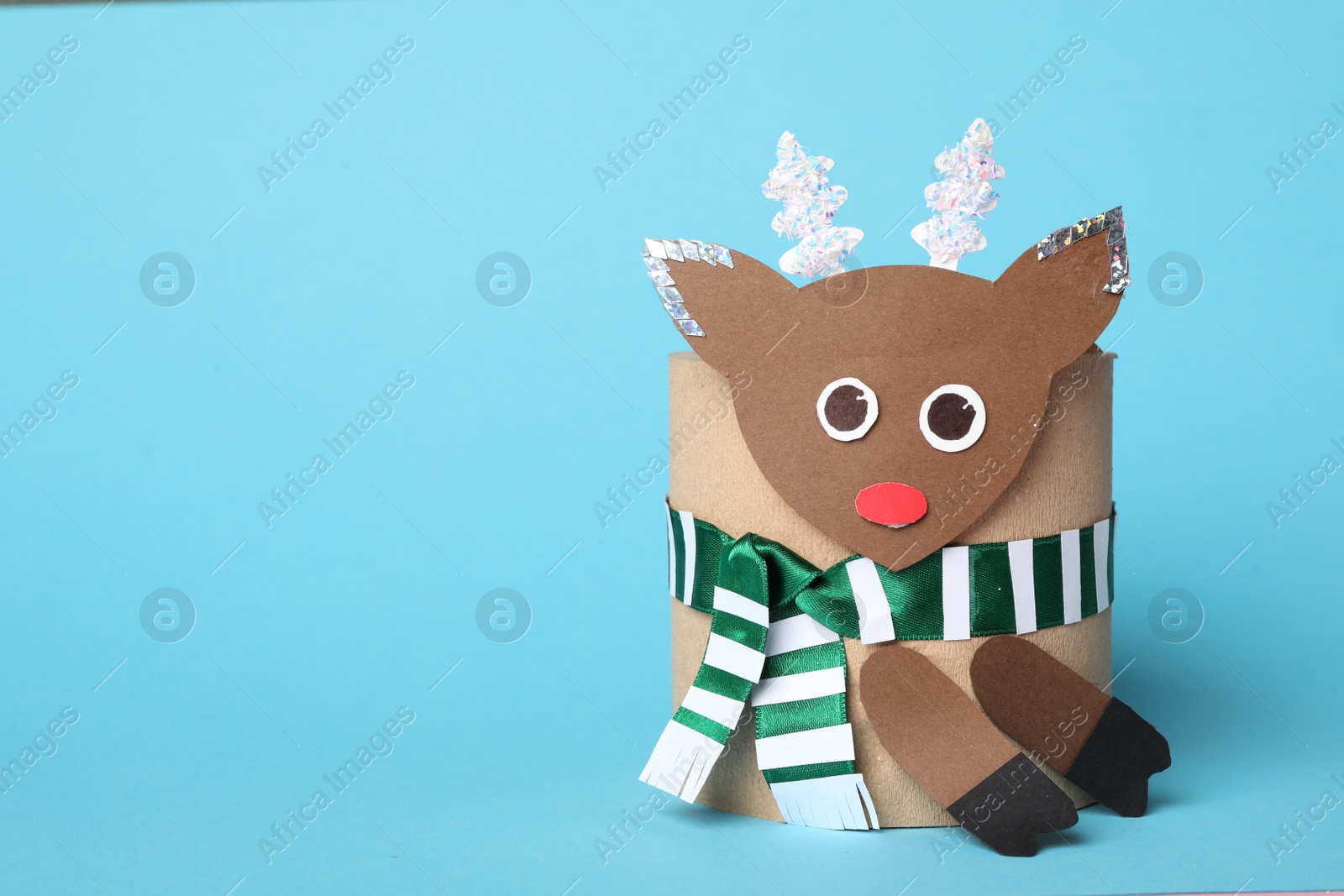 Photo of Toy deer made of toilet paper roll on light blue background. Space for text