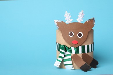 Photo of Toy deer made of toilet paper roll on light blue background. Space for text