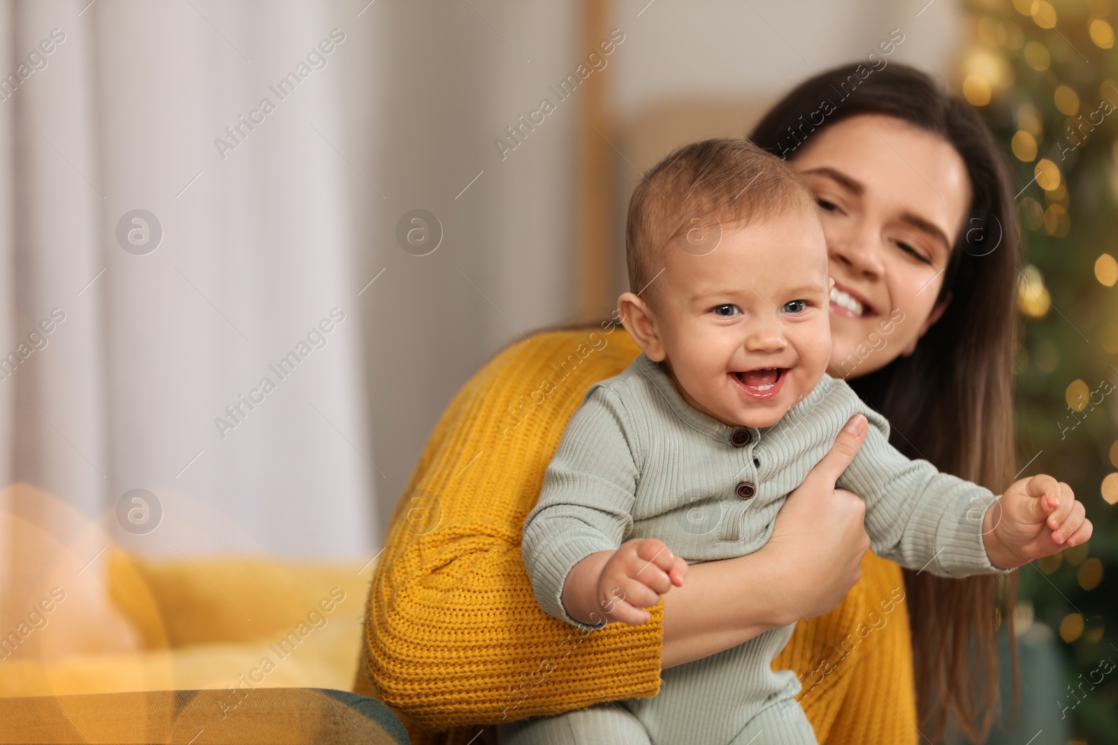 Photo of Happy young mother with her cute baby in room decorated for Christmas. Winter holiday