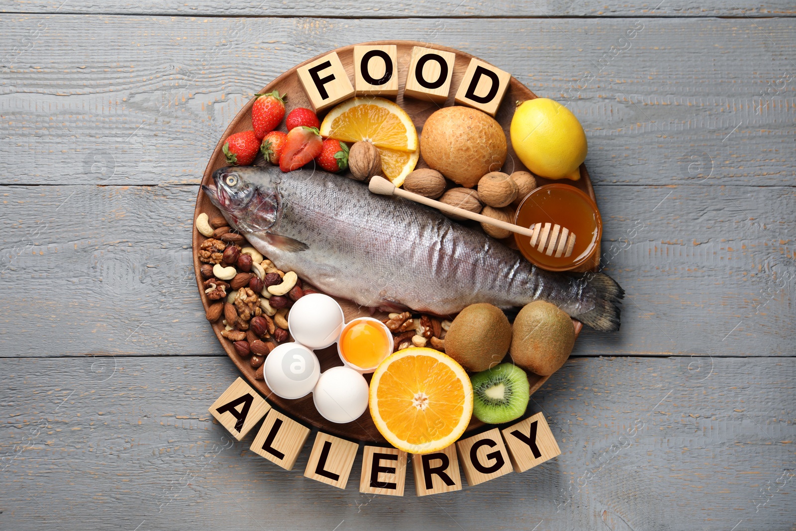 Image of Food allergy. Different fresh products and cubes on grey wooden table, top view