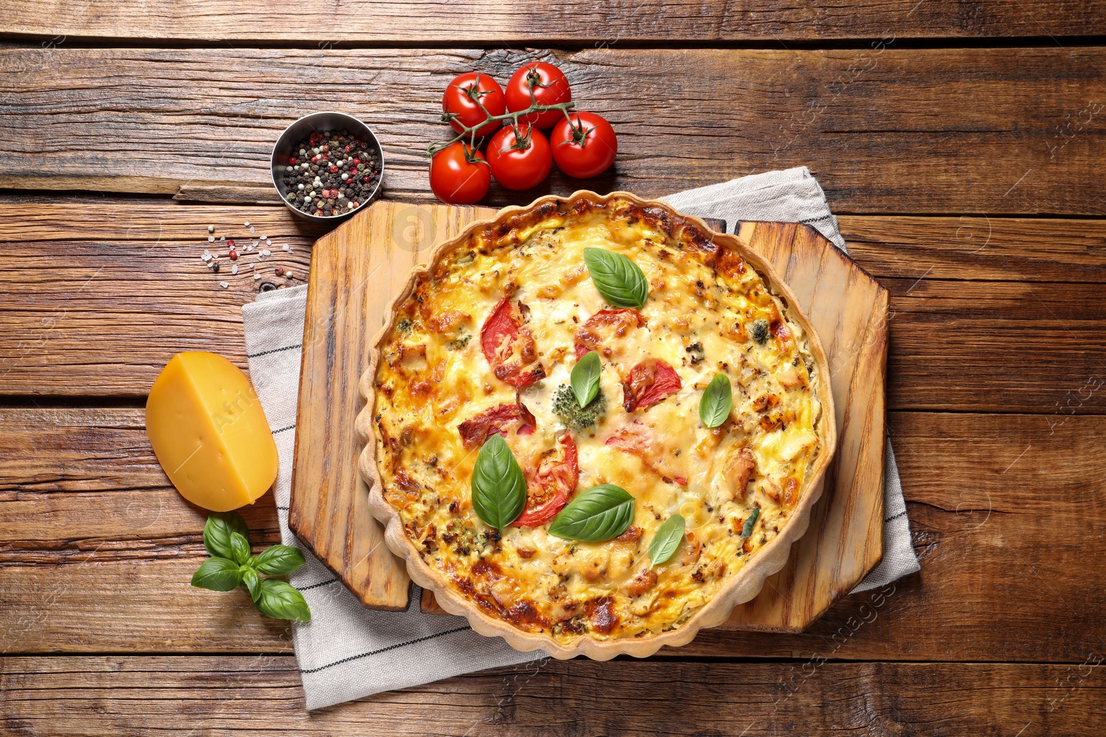 Photo of Tasty quiche with tomatoes, basil and cheese served on wooden table, flat lay