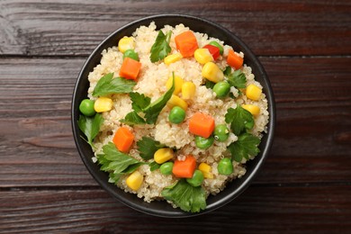 Photo of Tasty quinoa porridge with vegetables in bowl on wooden table, top view