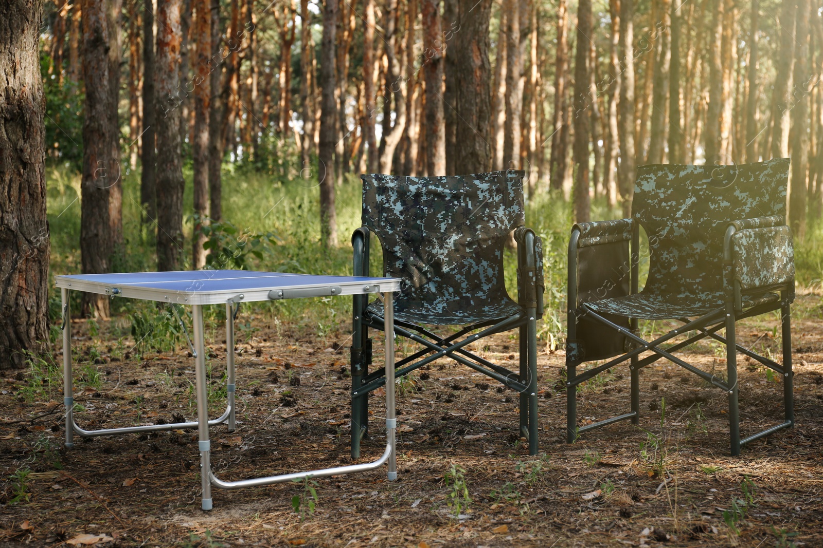 Photo of Camouflage chairs and table in forest on sunny day