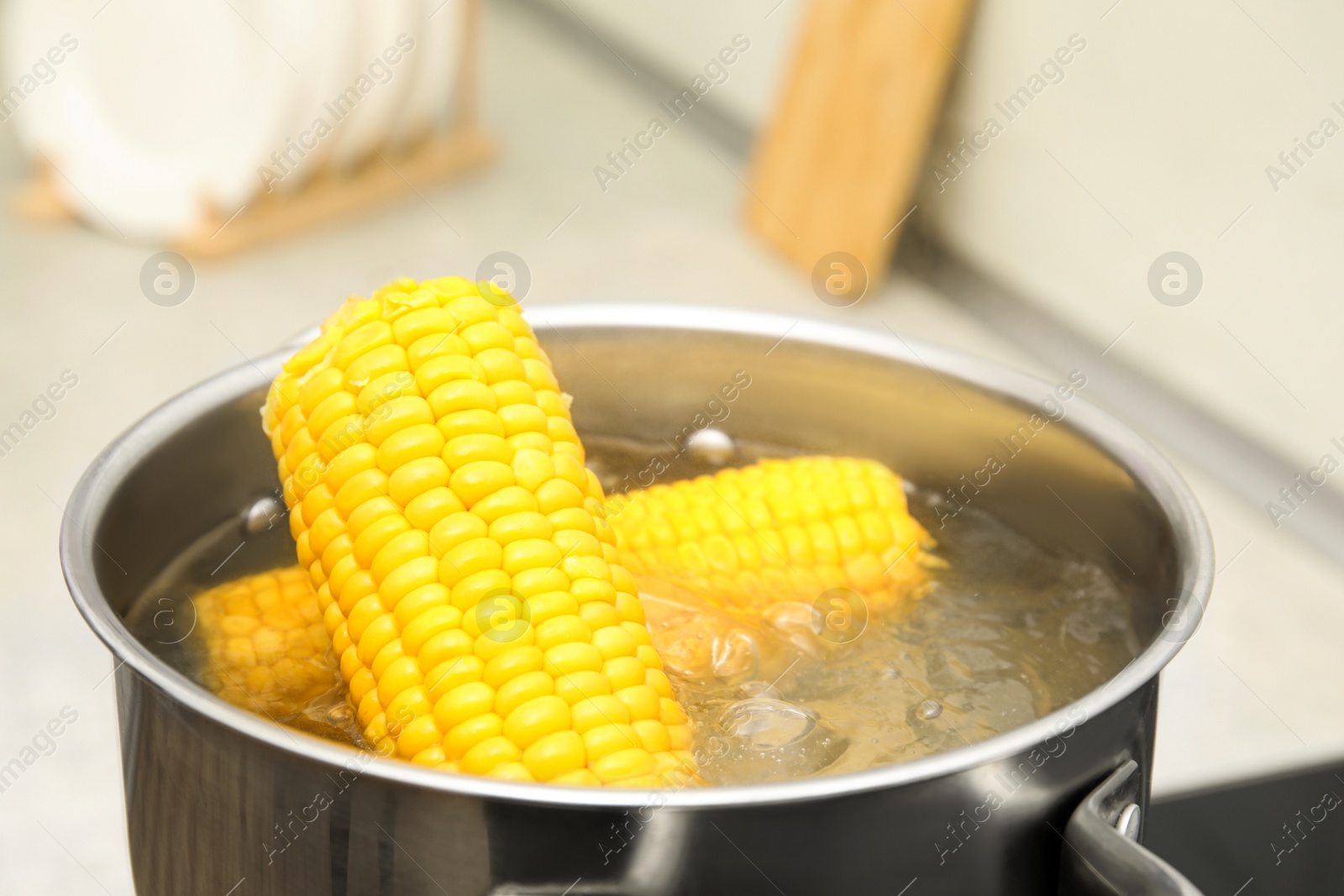 Photo of Pot with boiling corn in kitchen, closeup