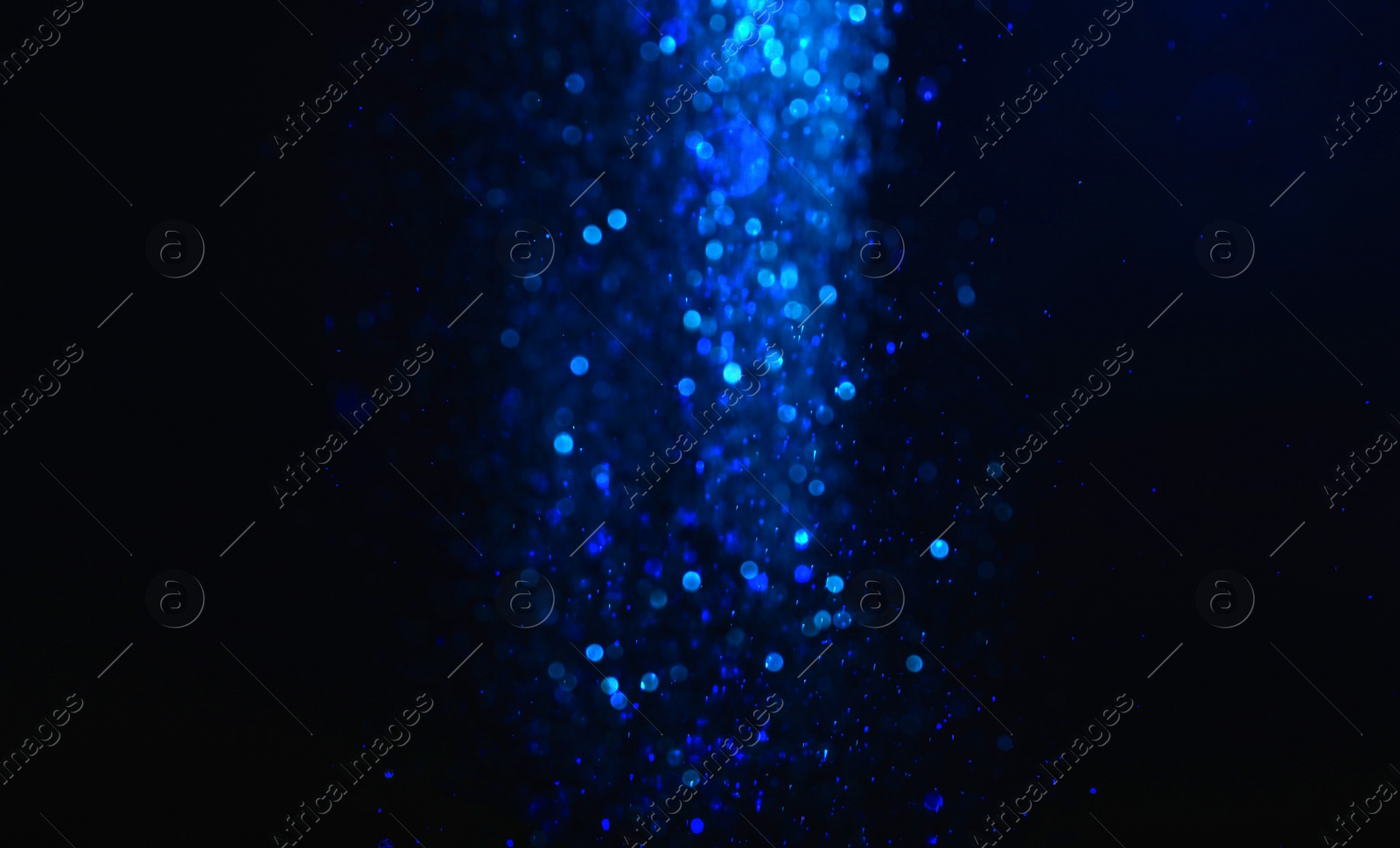 Photo of Shiny blue glitter falling down on black background. Bokeh effect