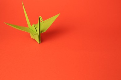 Photo of Origami art. Handmade paper crane on orange background, space for text