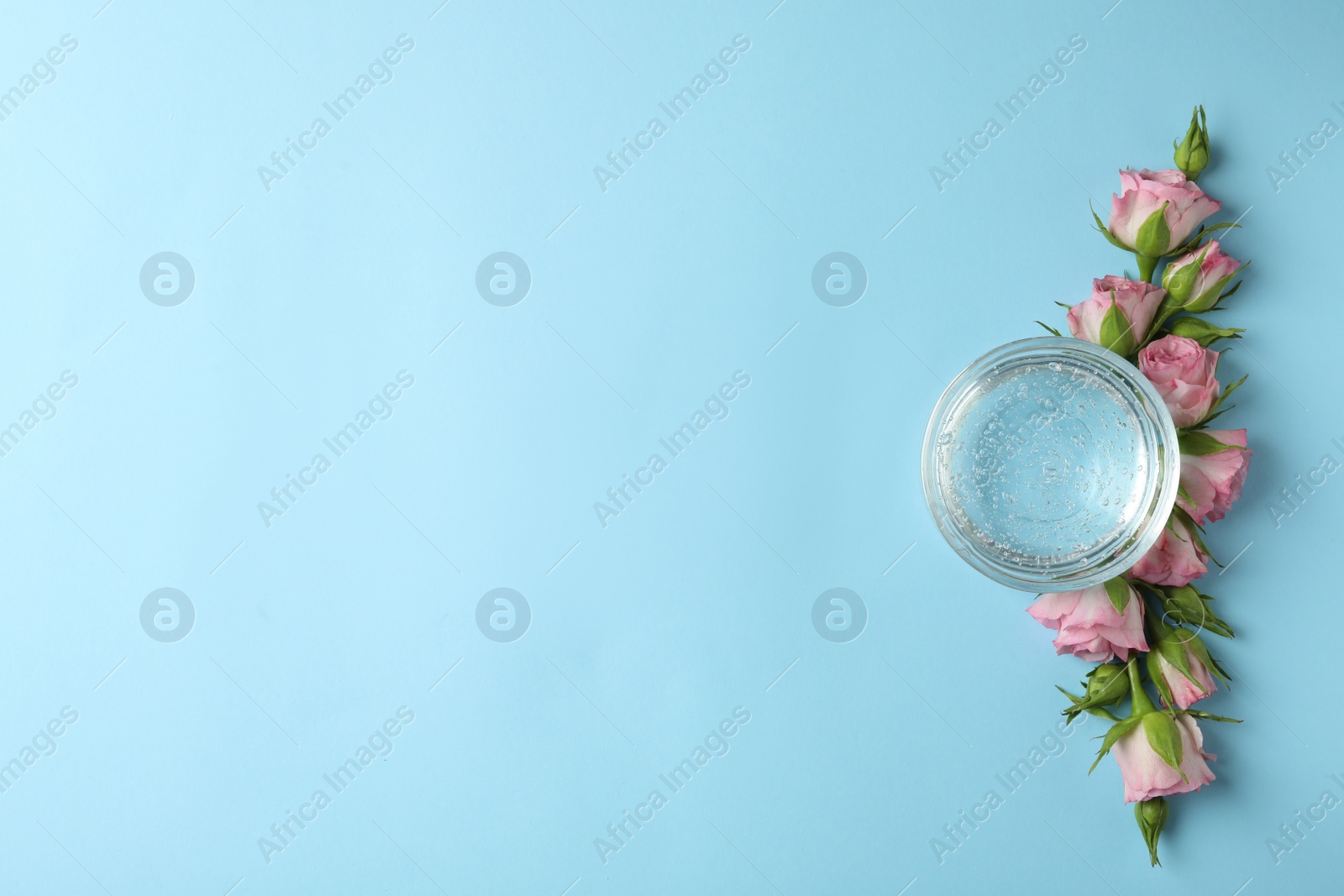 Photo of Flat lay composition with cosmetic gel and beautiful flowers on light blue background. Space for text