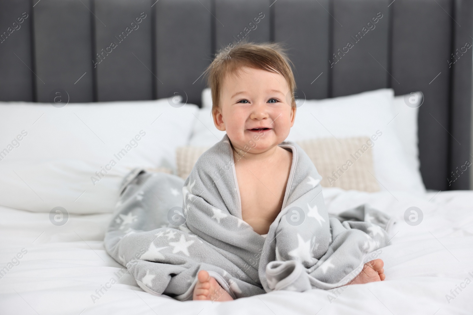 Photo of Happy baby boy with blanket sitting on bed at home