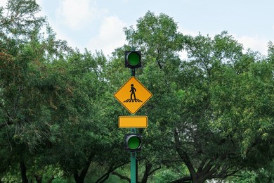 Photo of Road rules. Post with traffic lights and sign Pedestrian Crossing outdoors