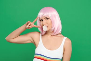Photo of Beautiful woman blowing bubble gum and gesturing on green background