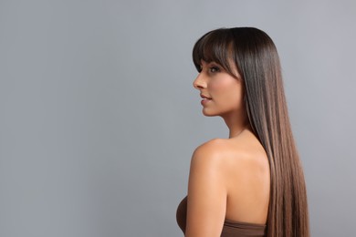 Photo of Hair styling. Beautiful woman with straight long hair on grey background, space for text