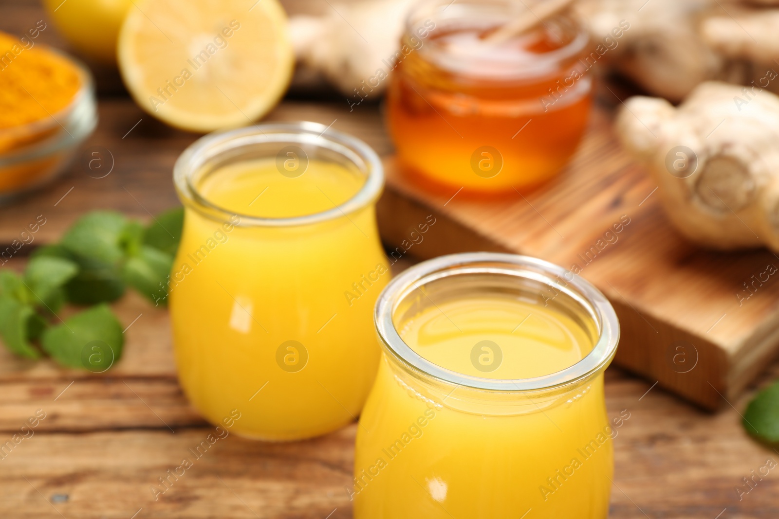 Photo of Immunity boosting drink and ingredients on wooden table, closeup