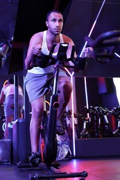 Young man training on exercise bike in fitness club