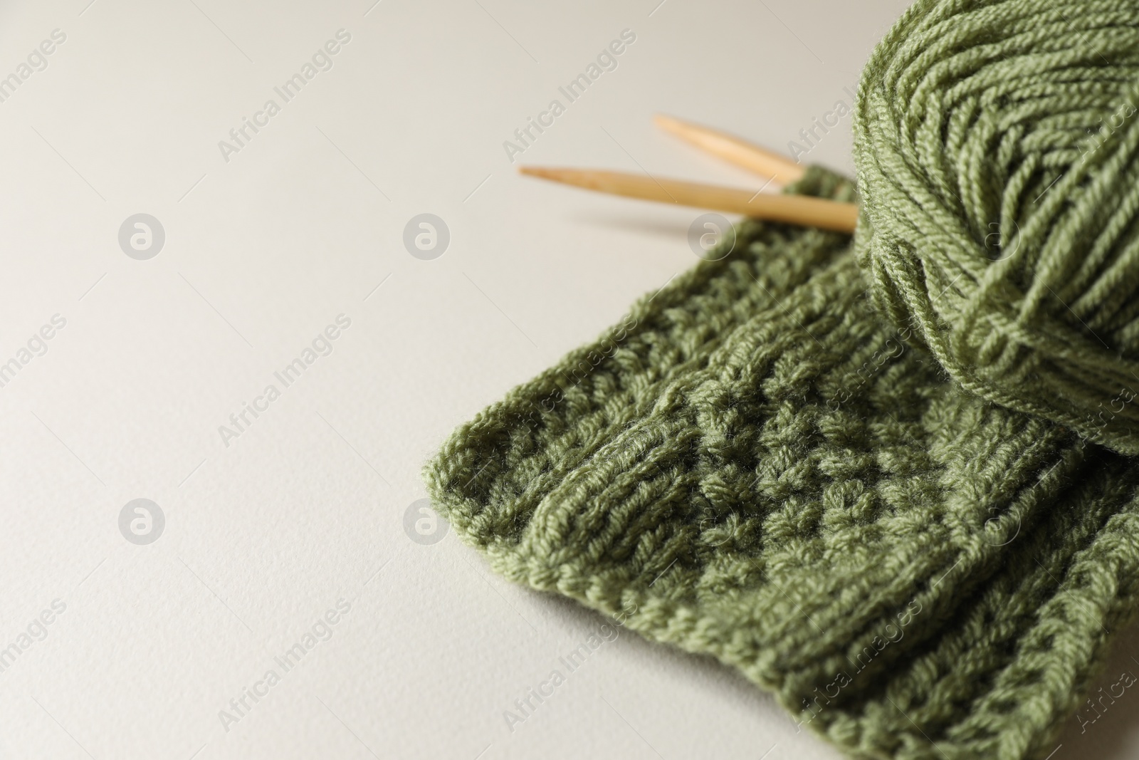 Photo of Knitting, soft yarn and needles on beige background, space for text