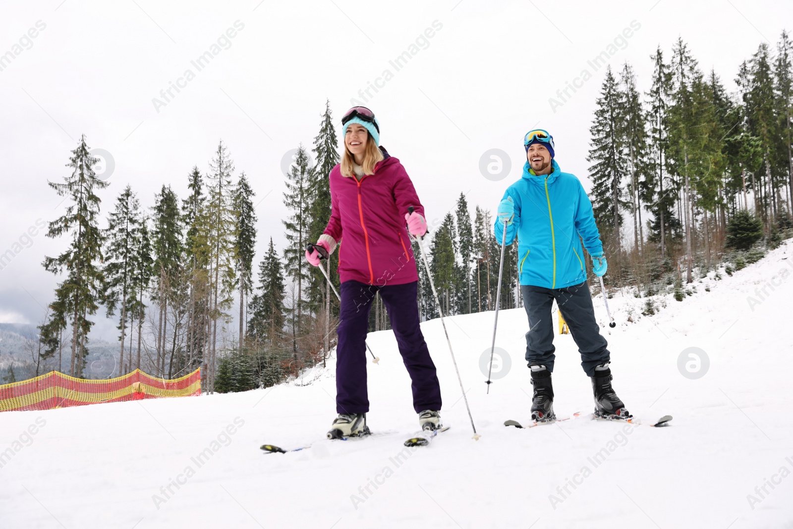 Photo of Couple of skiers on slope at resort. Winter vacation