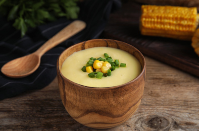 Photo of Delicious corn cream soup served on wooden table