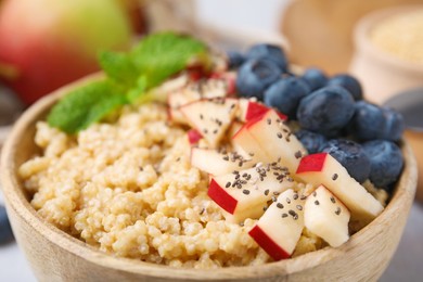 Photo of Bowl of delicious cooked quinoa with apples, blueberries and chia seeds, closeup