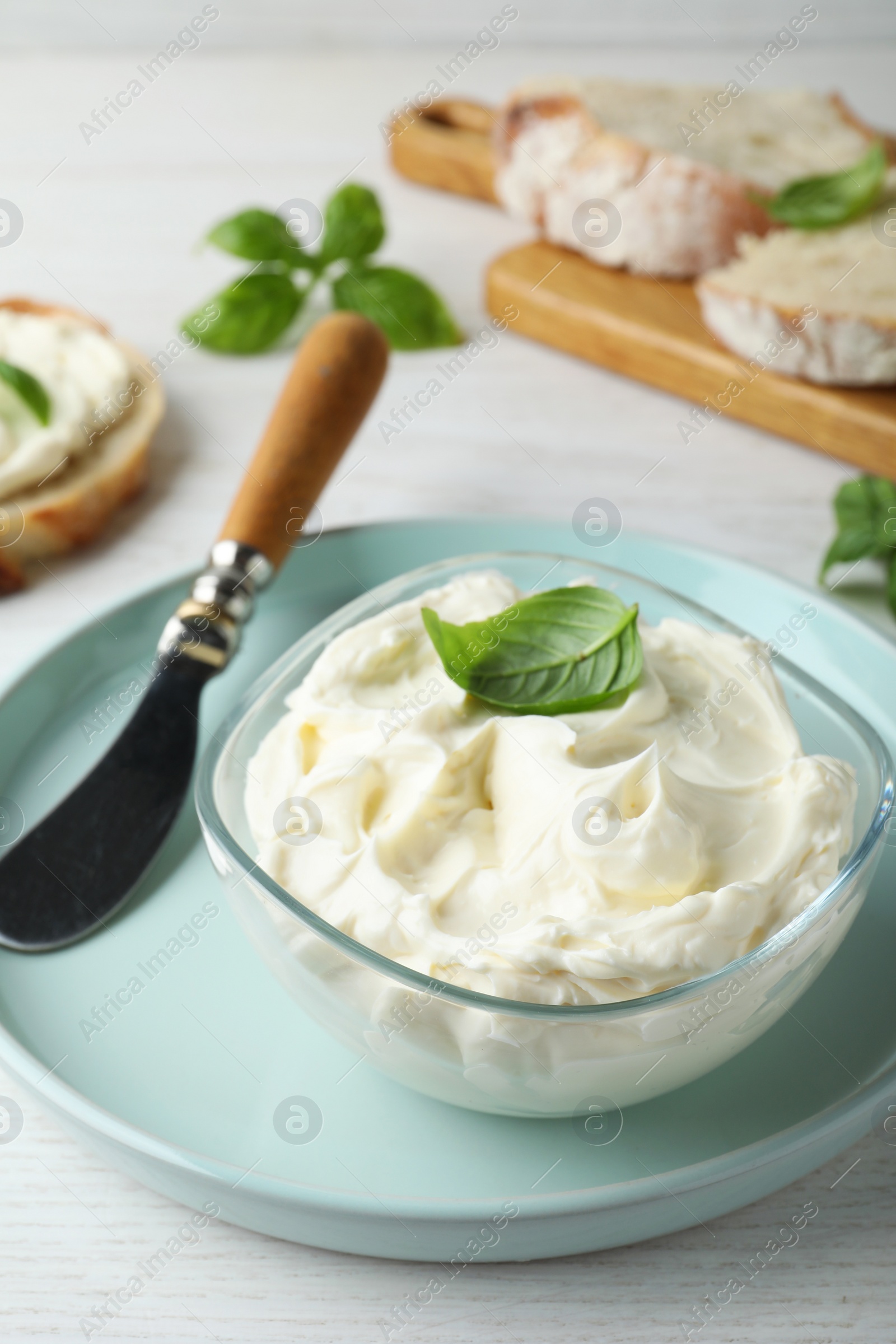 Photo of Tasty cream cheese with basil and knife on white wooden table