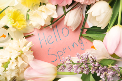 Photo of Card with words HELLO SPRING and fresh flowers on white background, flat lay
