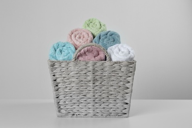 Wicker basket with clean soft towels on light background