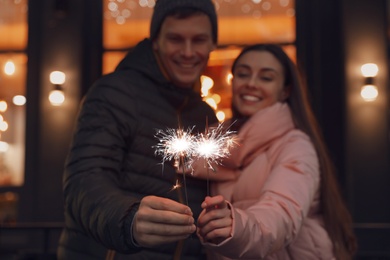 Happy couple with sparklers at winter fair