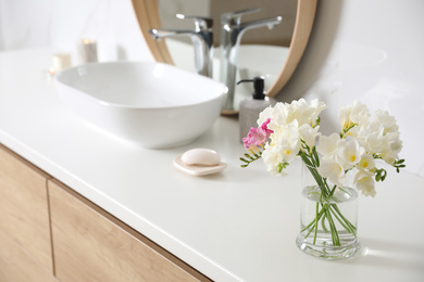 Photo of Beautiful bouquet with spring freesia flowers in bathroom, space for text