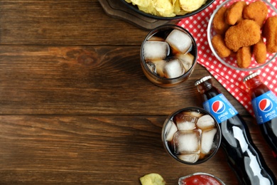 MYKOLAIV, UKRAINE - FEBRUARY 16, 2021: Pepsi and snacks on wooden table, flat lay. Space for text