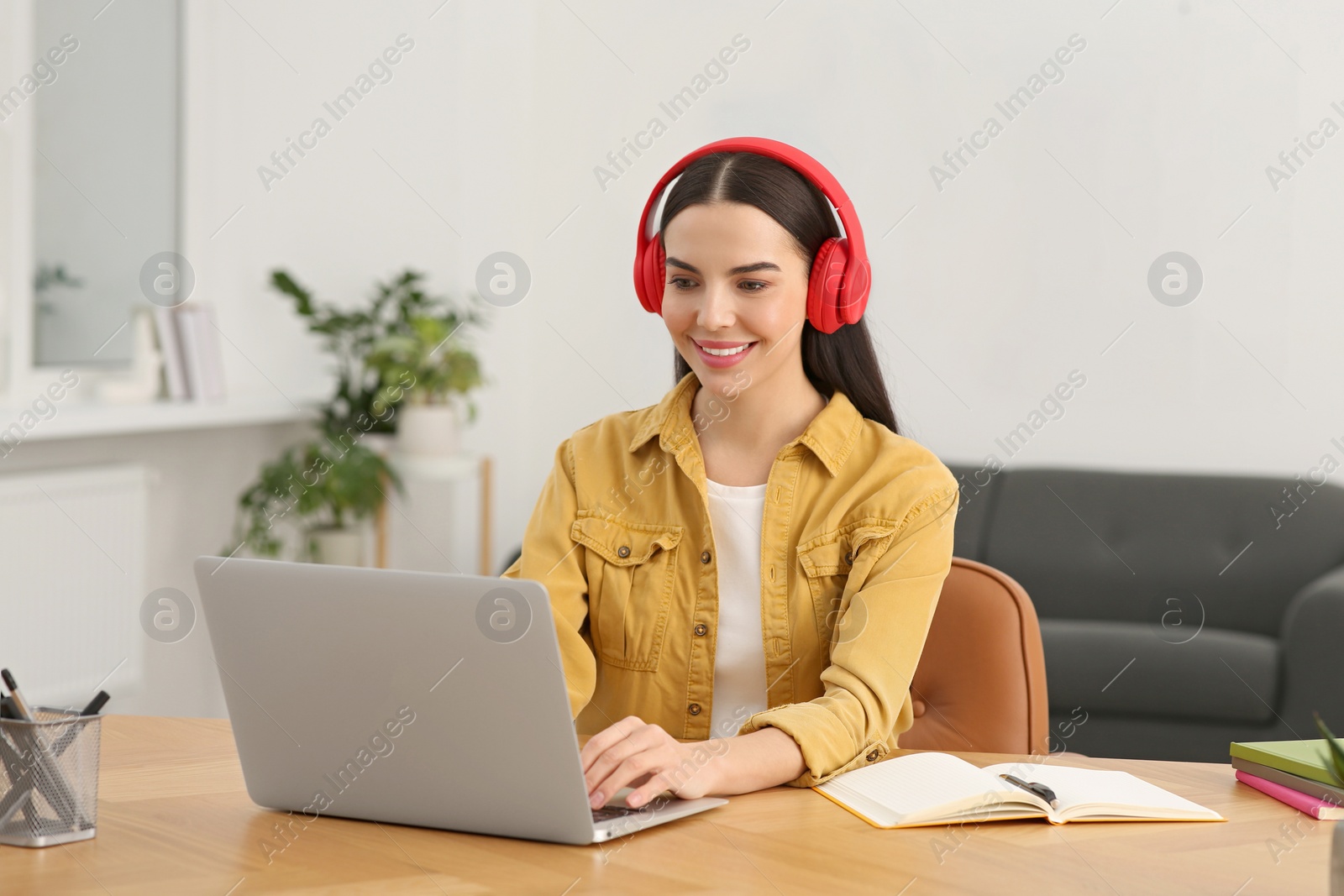 Photo of Online translation course. Student in headphones typing on laptop at home