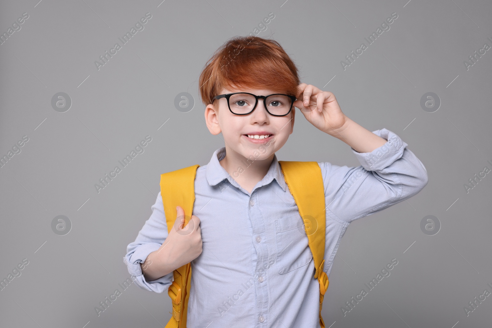 Photo of Happy schoolboy with backpack on grey background