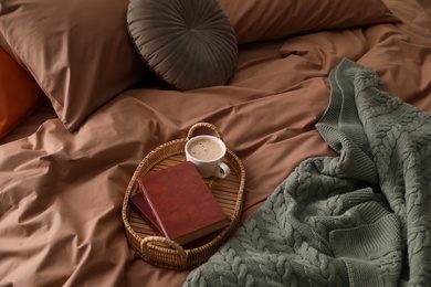Photo of Cup of hot coffee and books on bed with stylish linens, above view