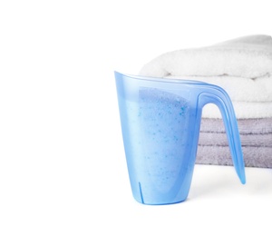 Photo of Laundry detergent in plastic measuring cup and towels on white background