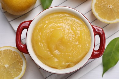 Delicious lemon curd in bowl and fresh citrus fruits on table, flat lay