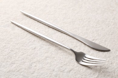 Stylish cutlery. Silver knife and fork on light textured table