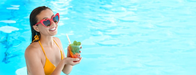 Image of Woman with glass of refreshing drink in swimming pool, space for text. Banner design