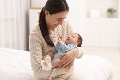 Mother with her sleeping newborn baby on bed at home