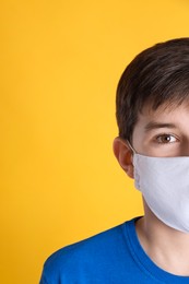 Photo of Boy wearing protective mask on yellow background, closeup. Child safety