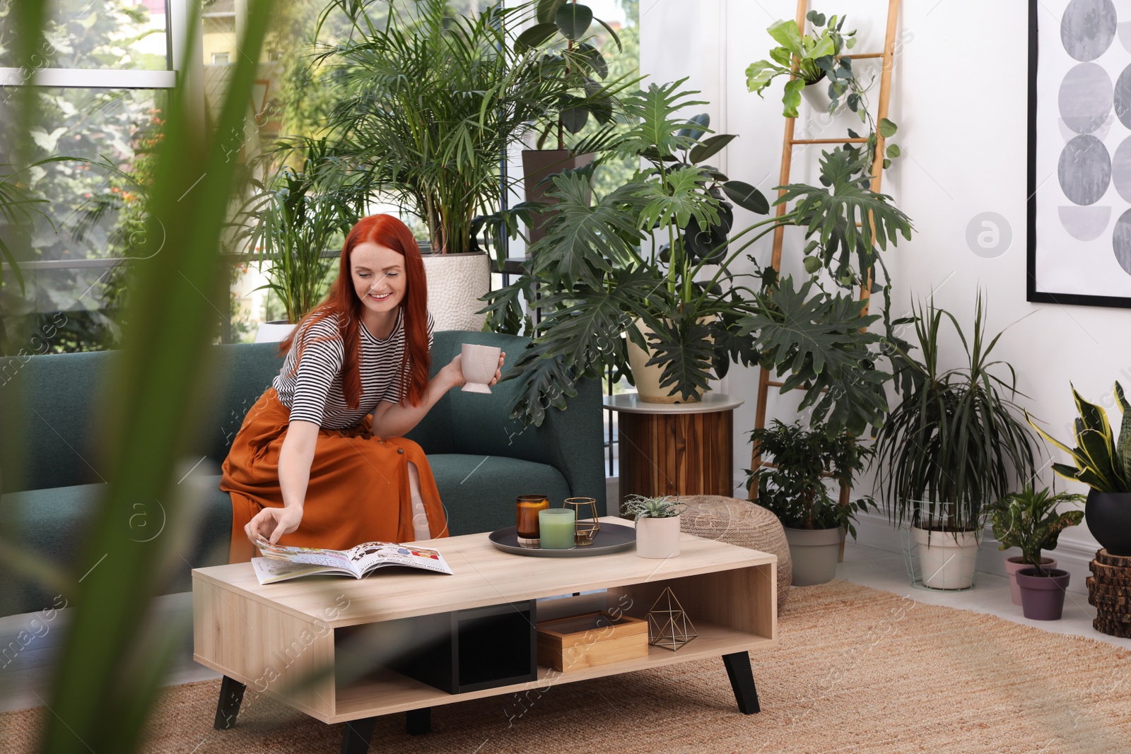 Photo of Beautiful woman with cup of tea on sofa in room