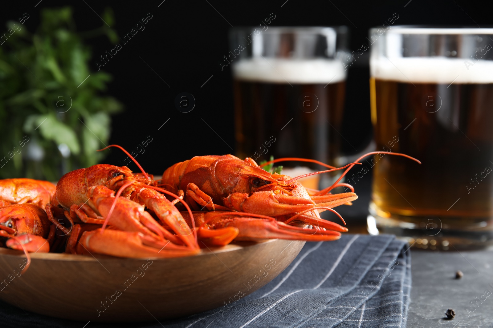 Photo of Delicious red boiled crayfishes on table against black background, closeup