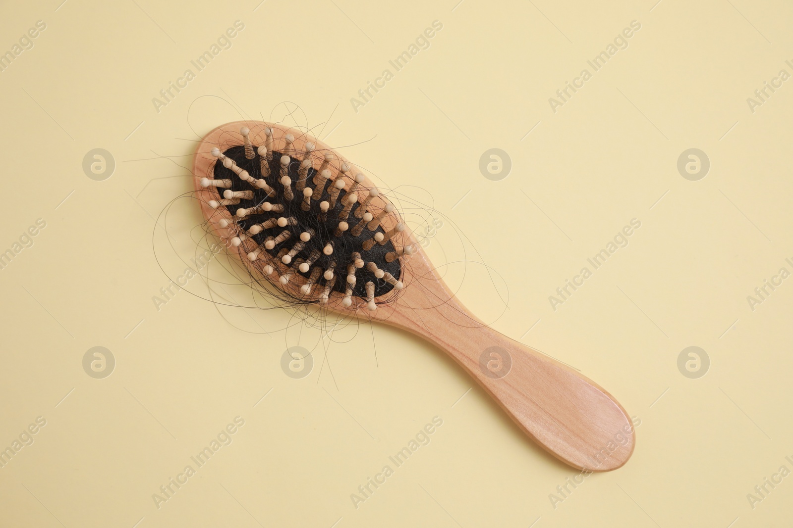 Photo of Wooden brush with lost hair on beige background, top view