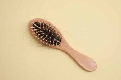 Photo of Wooden brush with lost hair on beige background, top view