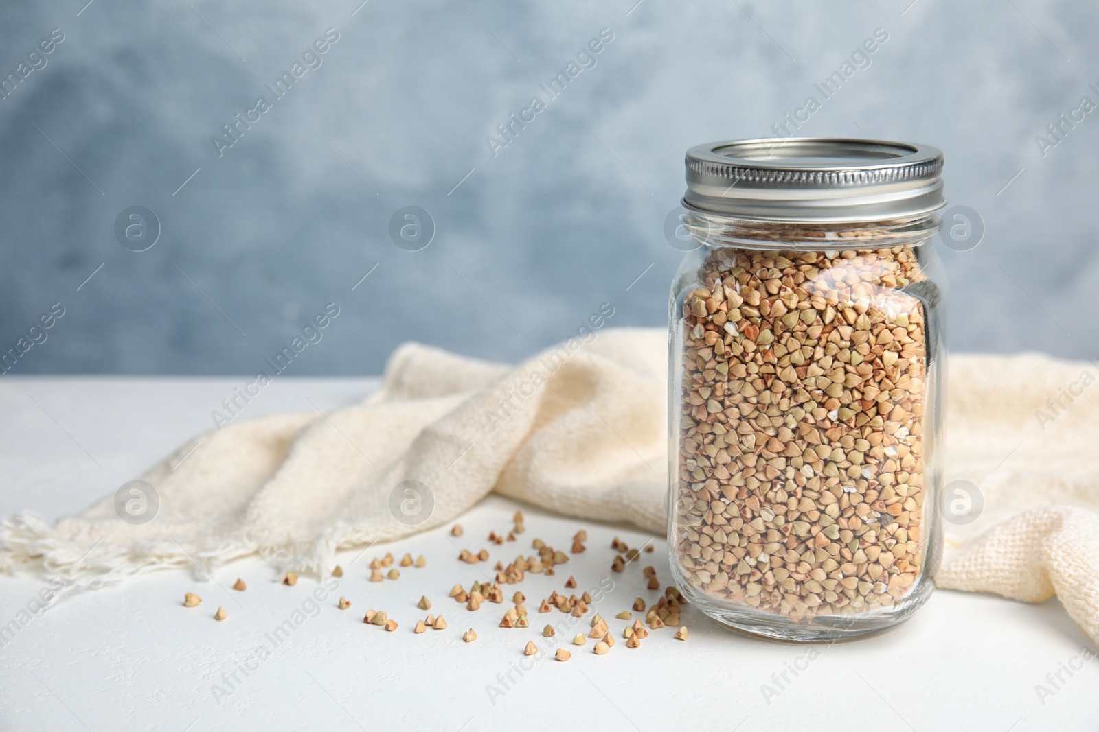 Photo of Jar with green buckwheat on white table. Space for text