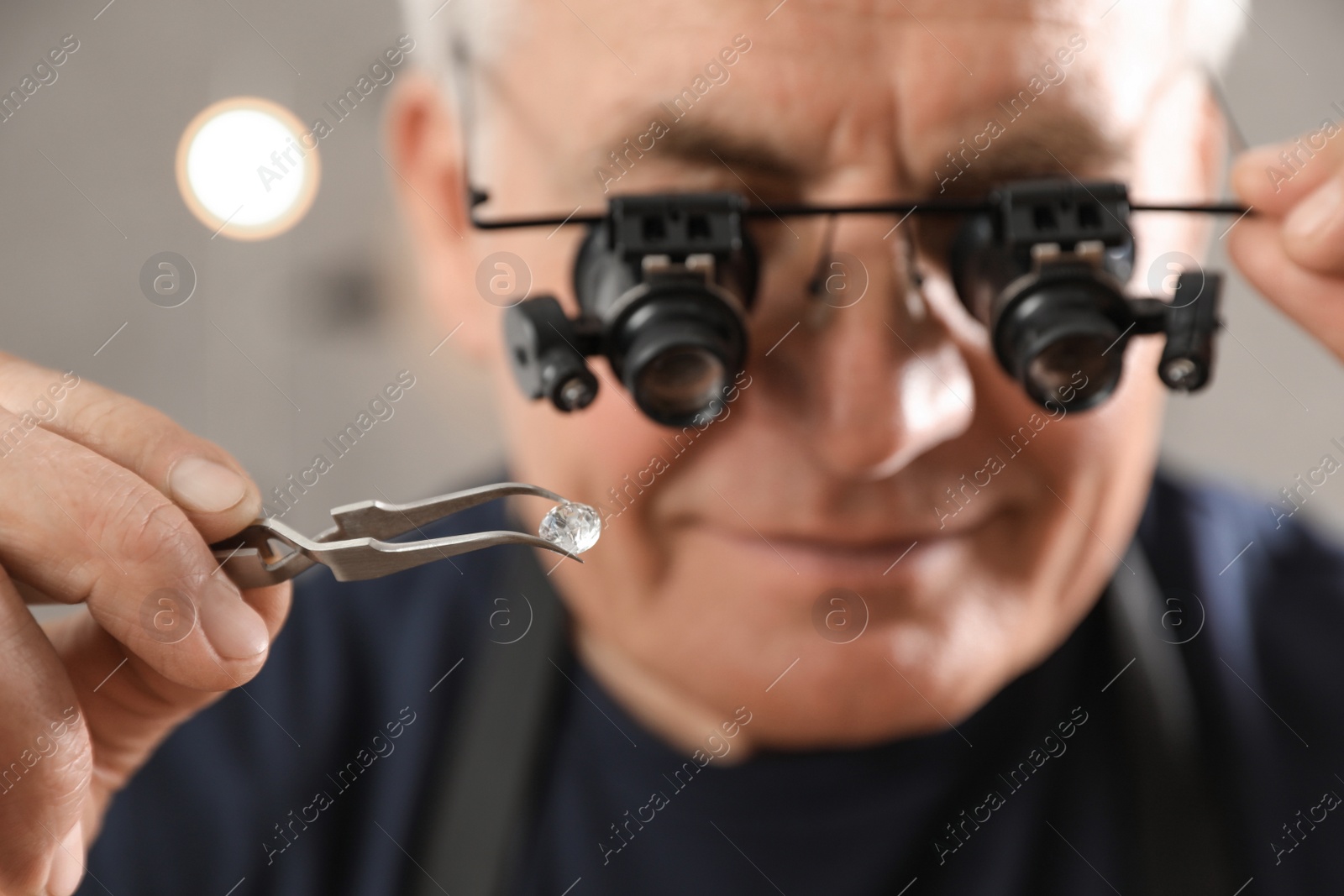 Photo of Male jeweler evaluating gemstone in workshop, closeup