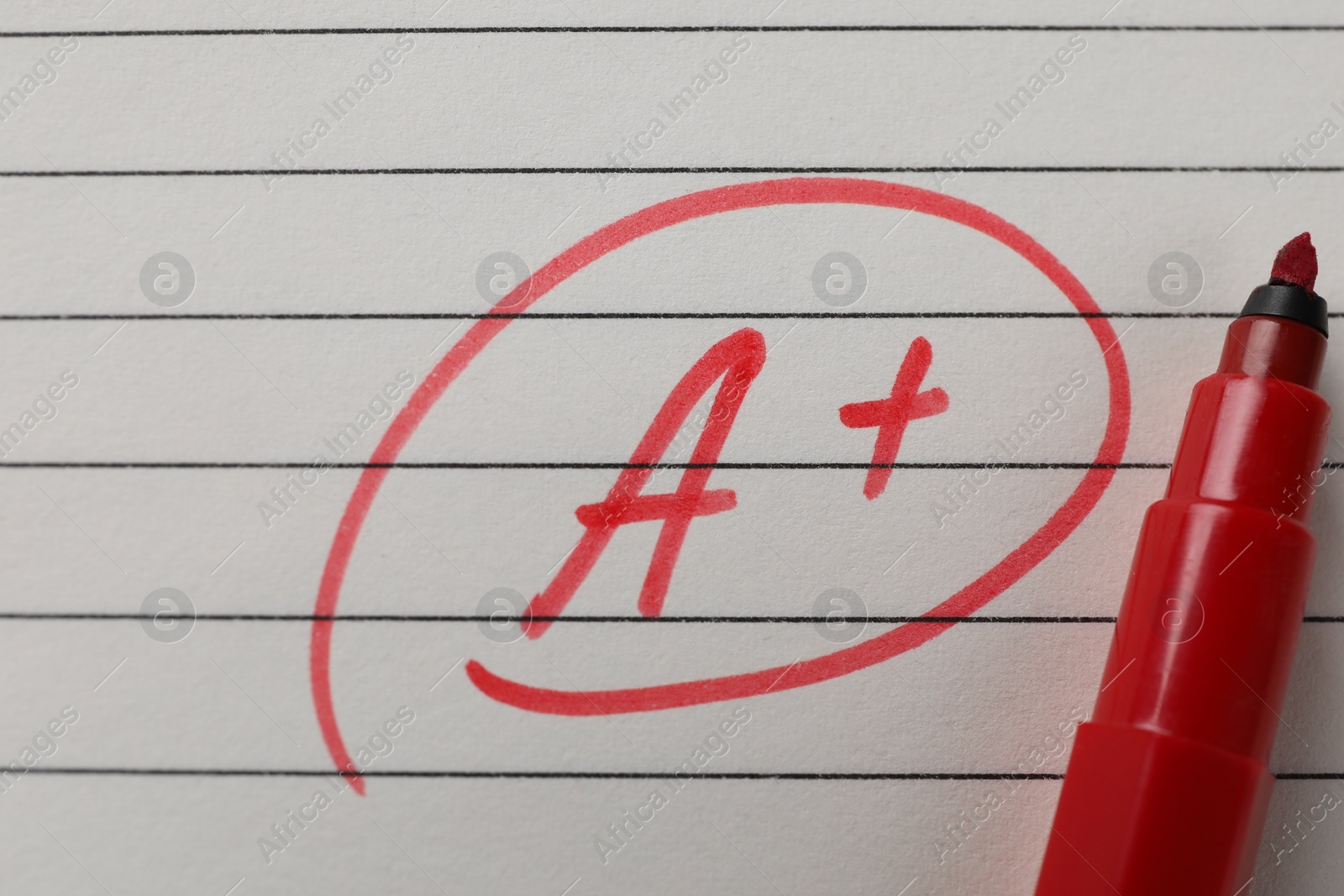 Photo of School grade. Red letter A with plus symbol on notebook paper and marker, top view