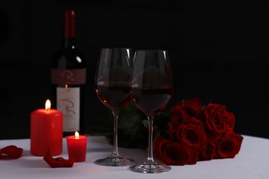 Photo of Romantic table setting with glasses of red wine, rose flowers and burning candles